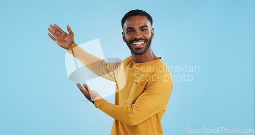 Image of Happy, face and man with hand pointing in studio for news, presentation or platform offer on blue background. Smile, portrait and male model show promo, launch or space for coming soon announcement