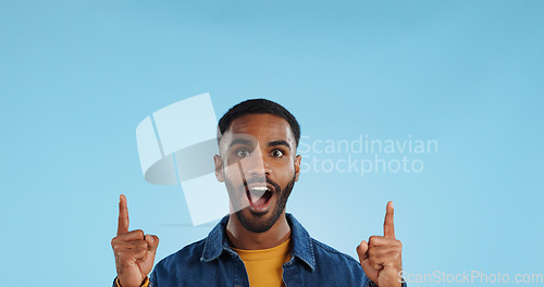 Image of Happy man, pointing and news announcement with portrait in studio, surprise emoji and advertising. Mockup, mexican person and smiling in casual fashion for offer and notification by blue background