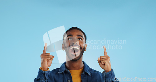 Image of Happy man, pointing and news announcement with portrait in studio, surprise emoji and advertising. Mockup, mexican person and smiling in casual fashion for offer and notification by blue background