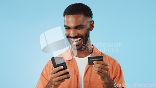 Image of Man, credit card and excited with phone, studio and thinking of sale, promo code or info by blue background. Online shopping, easy payment and happy for financial freedom, fintech app or smartphone