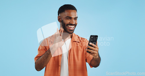 Image of Video call, wave and man with a smartphone, showing and conversation on a blue studio background. Person, speaking and model with a cellphone, online chat and communication with network or connection