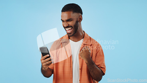 Image of Man, fist celebration and phone in studio for esports, gambling and profit with trading by blue background. African person, investor and smartphone with fintech app, lotto and revenue on stock market