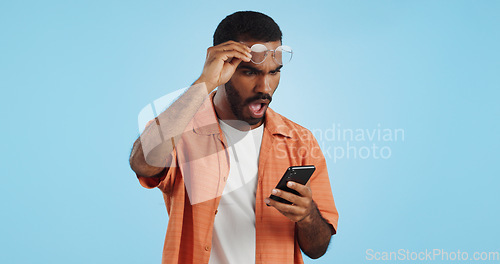 Image of Man, smartphone and surprise announcement with shock, facial expression and drama online on blue background. Wow, reaction to news on social media and communication, mobile app and alarm in studio