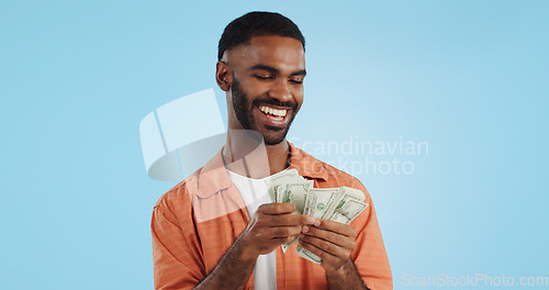 Image of Man, count money and happy in studio with success, bonus or dollar promotion with winning by blue background. Investor, trader or person with cash, salary or savings with smile for financial freedom