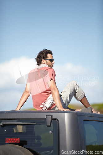 Image of Road trip, man and sitting on van roof for scenery, nature and fresh air on adventure or vacation in South Africa. People, tourist or traveler on rooftop of van with sunglasses for view or journey