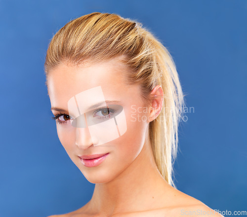 Image of Portrait, beauty and ponytail of a woman closeup in studio on a blue background for skin wellness or cosmetics. Face, skincare and cosmetics with a natural young model at the salon for dermatology