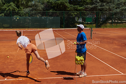 Image of A professional tennis player and her coach training on a sunny day at the tennis court. Training and preparation of a professional tennis player