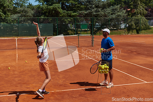 Image of A professional tennis player and her coach training on a sunny day at the tennis court. Training and preparation of a professional tennis player