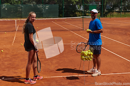 Image of A professional tennis player and her coach training on a sunny day at the tennis court. Training and preparation of a professional tennis player