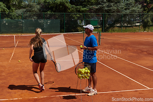 Image of A professional tennis player and her coach training on a sunny day at the tennis court. Training and preparation of a professional tennis player