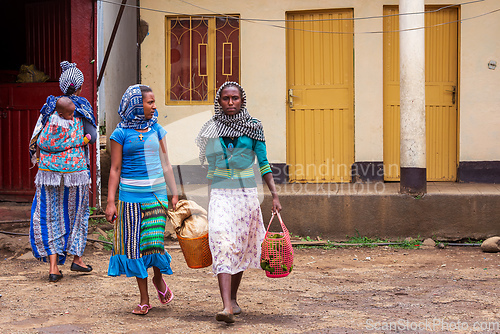 Image of An authentic snapshot of urban life in Bahir Dar, showcasing a woman walking down the vibrant streets with a shopping bag.