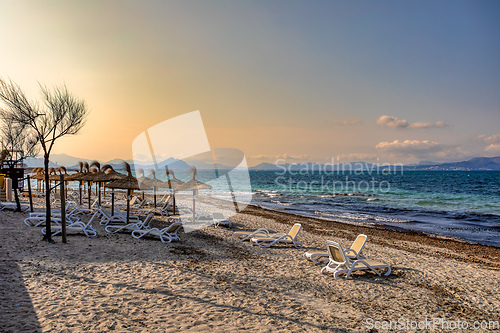 Image of Can Picafort Beach with straw umbrellas and sun loungers, Can Picafort, Balearic Islands Mallorca Spain.