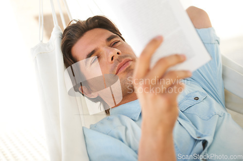 Image of Reading, relaxing and young man on a hammock with a book for information or knowledge in backyard. Resting, calm and male person enjoying a story or novel on a body swing outdoor at modern apartment.