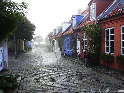 Image of Cottage, cobblestone road and village, travel and neighborhood in Denmark with landscape or background. Traditional, town and tourism with street, property or houses, architecture and countryside