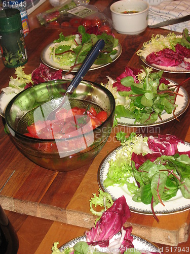 Image of Salad on plates and tomatos in a bowl