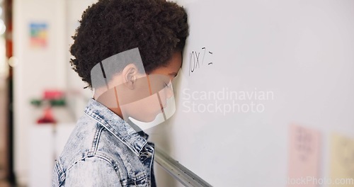 Image of Math class, sad child at board for education, learning and problem solving for skill development. Boy at whiteboard in classroom with struggle, thinking and stress at school for solution in knowledge