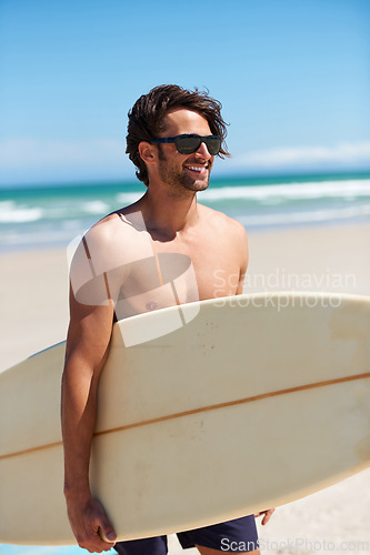 Image of Man, surfing and happy on vacation with sunglasses by the beach and sea for fitness and water sport with smile. Confidence, male person and surfboard for workout and training by ocean with freedom