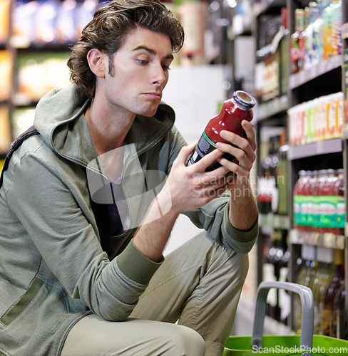 Image of Man, label and product in supermarket for decision, consider or grocery shopping nutrition choice. Male person, thinking and bottle shelf store search or reading price, diet value or buy organic