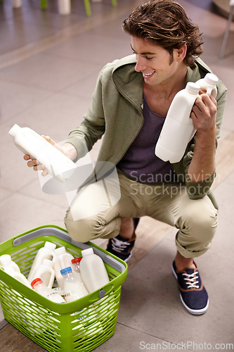 Image of Man, milk and product comparison in grocery store, choice or shopping basket selection. Male person, smile and dairy drink for supermarket decision, expiry date information or reading nutrition value