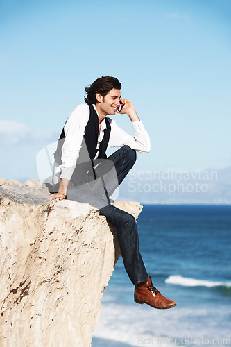 Image of Cliff, edge and man with a happy phone call at the ocean, beach or connection on vacation, travel or social media. Businessman, contact and edgy chat on cellphone, communication or talking above sea