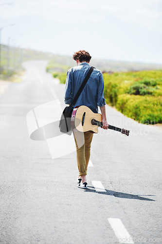 Image of Musician, walking and man with a guitar on a road trip, journey or tour in the countryside on highway. Guitarist, travel or back of guy trekking on street or asphalt in a green and rural landscape
