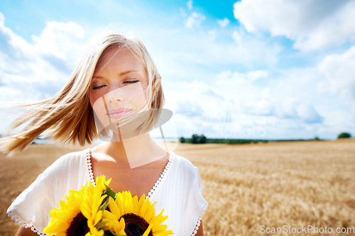 Image of Freedom, nature and calm woman with a sunflower on a wheat field for travel or vacation. Peace, face and female person in nature with a flower in countryside for holiday, journey or adventure outdoor