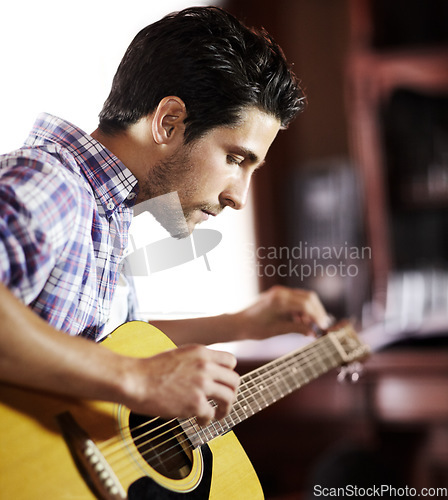 Image of Guitar, tuning or man in house for music, performance or entertainment in living room with talent. Learning solo, acoustic strings or creative musician playing an instrument for artistic expression