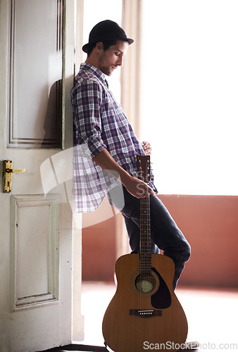 Image of Musician, waiting and man with a guitar, instrument and singer in a music studio. Creative, artist and guitarist standing in home and thinking of performance, equipment or listening to audio of band