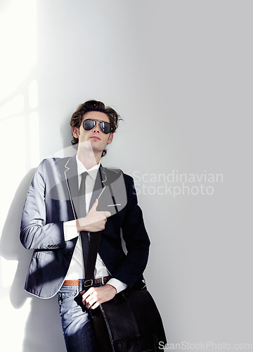 Image of Fashion, elegant and handsome man by a wall with stylish, cool and trendy outfit and briefcase. Sunglasses, bag and young male model from Canada with formal and classy style by white background.