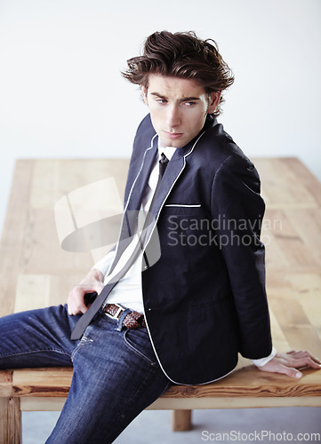 Image of Fashion, table and attractive man in a studio with formal, classy and elegant outfit for aesthetic. Handsome, suit and serious young male model with trendy and cool style for clothes by wooden desk.