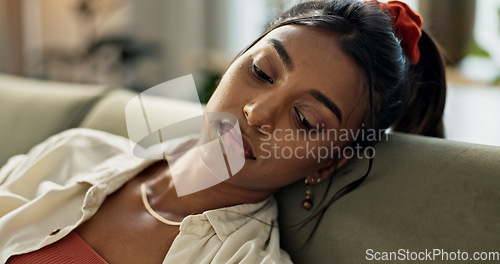 Image of Depression, anxiety and young woman on a sofa relaxing with an idea or memory in living room. Anxious, mental health and nervous Indian female person with reflection in the lounge of modern apartment