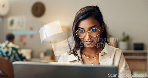 Image of Business, woman and reading on laptop in office for research, feedback and supply chain for business. Indian, person and typing on pc for logistics, stock administration or package distribution data