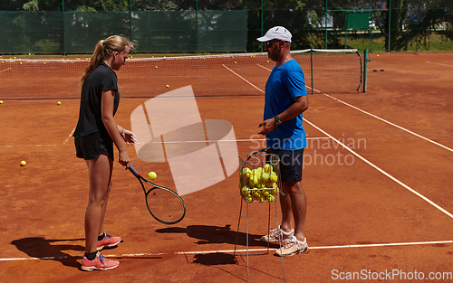 Image of A professional tennis player and her coach training on a sunny day at the tennis court. Training and preparation of a professional tennis player