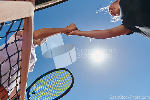 Image of Two female tennis players shaking hands with smiles on a sunny day, exuding sportsmanship and friendship after a competitive match.