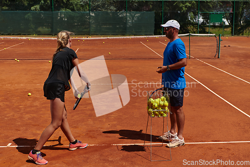 Image of A professional tennis player and her coach training on a sunny day at the tennis court. Training and preparation of a professional tennis player