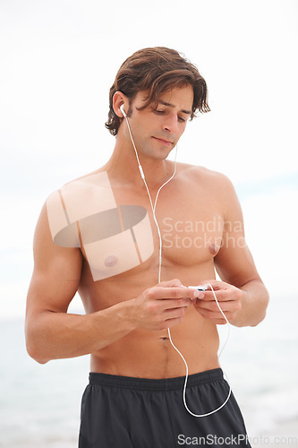 Image of Man, muscle and music on beach or exercise listening audio for sea air, playlist or running entertainment. Male person, radio and streaming song player or fresh ocean, weekend training or summer fun