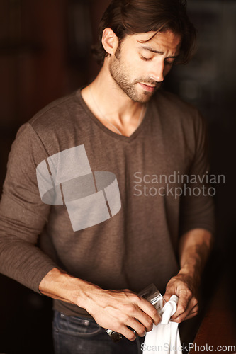 Image of Bartender, man and polish glass in restaurant, cafe or small business to prepare in cafeteria. Cleaning, cloth and barman wipe cup, employee or professional waiter work in pub, coffee shop or service