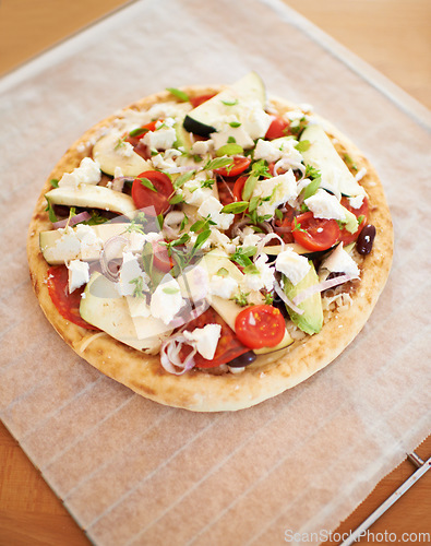 Image of Healthy, vegan and pizza on table in kitchen, home or cooking with pita, cheese and tomato. Vegetable, flatbread and homemade food from Italy with nutrition in diet, meal or lunch on counter in house