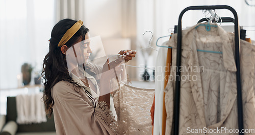Image of Woman, clothes rack and choice for fashion, retail management and small business in store or boutique. Young worker, entrepreneur or designer with stock, inventory and luxury dress or product on rail