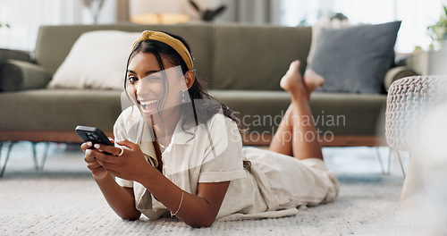 Image of Woman, phone and portrait with wink, relax and lying on floor for flirting, secret and typing in living room of home. Indian, girl and smartphone on ground for chat, texting or technology with emoji