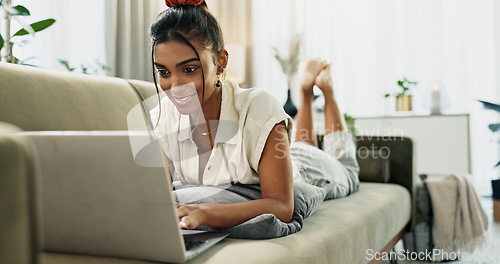 Image of Woman, laptop and typing on sofa, relax and reading for search, thinking or e learning in home living room. Student, girl and computer on lounge couch, online course or happy for post on social media