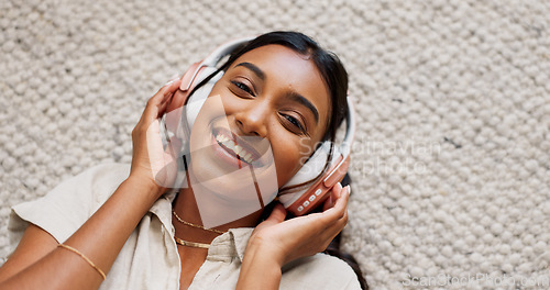 Image of Headphones, smile and portrait of woman in the living room relaxing on mat on floor. Happy, calm and Indian female person listen to podcast, radio or music and chilling in lounge at home from above.