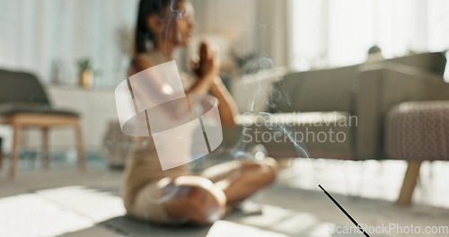 Image of Woman, yoga and incense with lotus pose on living room floor for zen, mental health and wellness in house. Indian, person or breath with praying hands for chakra training, relax or home in meditation