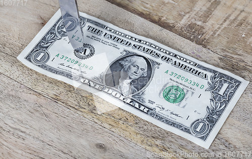 Image of one American dollar pierced with a knife