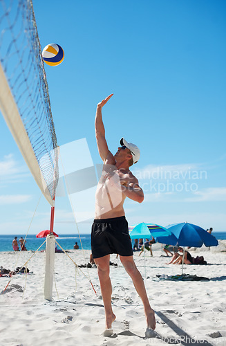 Image of Volleyball, man and fitness at beach with ball serve, energy or freedom on blue sky background. Seaside, sports or male player with handball in nature for cardio, workout or athletic game performance