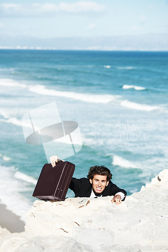 Image of Climbing cliff, problem or businessman with stress for job, career opportunity or work crisis at beach. Professional, frustrated or corporate worker hanging on edge with anxiety, briefcase or danger