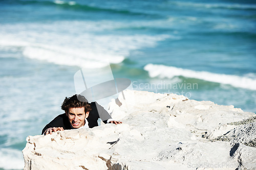 Image of Climbing cliff, frustrated or businessman with stress for job, career opportunity or work crisis at beach. Professional, ocean or corporate worker hanging on edge with anxiety, depression or danger