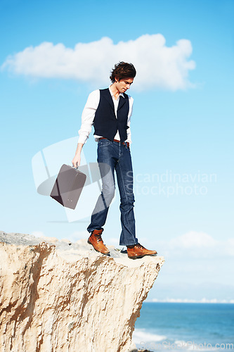 Image of Business man, summer and standing on a cliff by the beach for adrenaline, adventure or a break in nature. Thinking, walking and a worker or person on the edge of a rock or mountain at the ocean