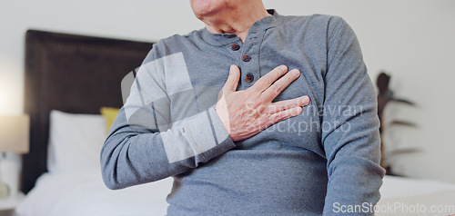 Image of Hands, chest pain and closeup of senior man in bedroom with injury, hurt or accident at nursing home. Sick, ill and zoom of elderly male person in retirement with asthma or heart attack at house.