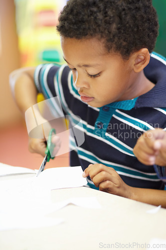 Image of Boy, classroom and scissor for cutting paper with learning, thinking and development in kindergarten. African child, education and ideas at preschool academy for skills, scholarship or knowledge